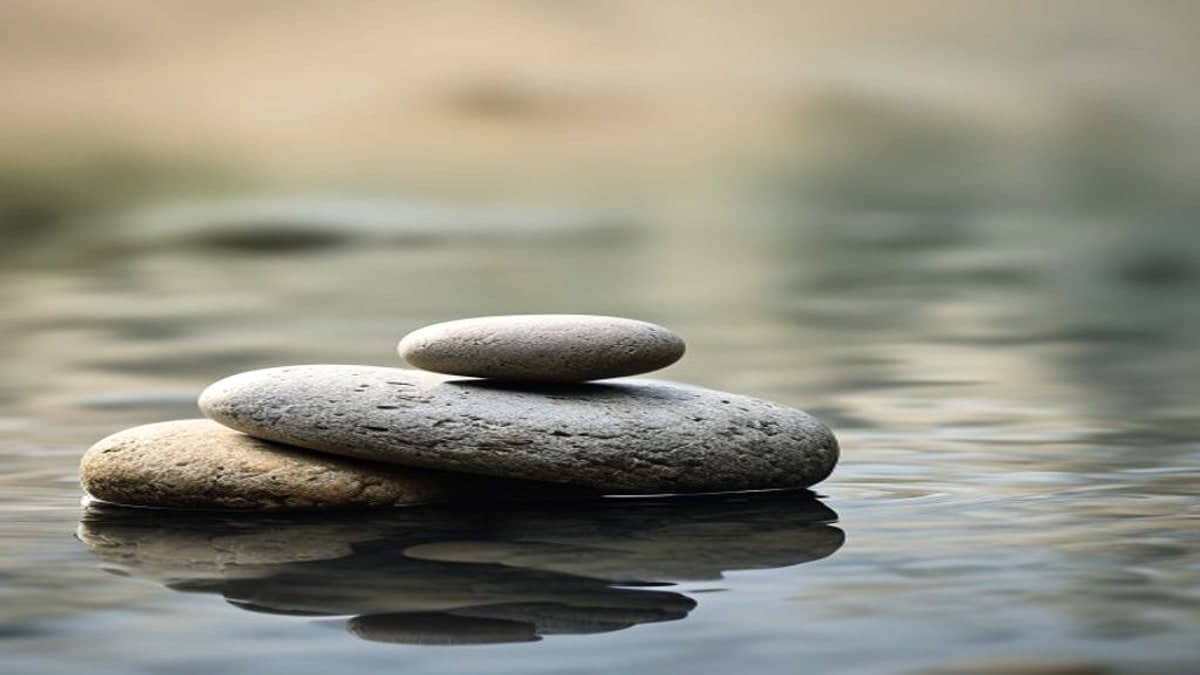 Soft water surface with rounded stones in calm light
